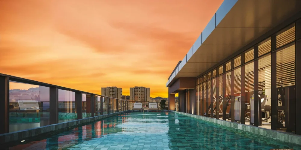 Deck molhado do rooftop do Céu Laranjeiras ao pôr do sol, integrando a piscina à academia com vista panorâmica da cidade.