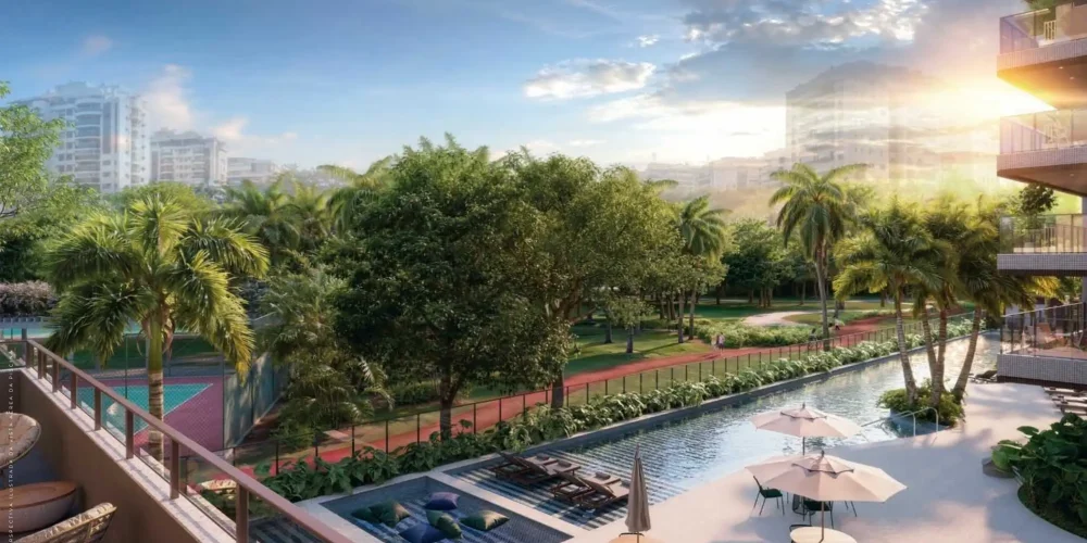 Vista panorâmica do empreendimento Gran Thai Península na Barra da Tijuca, com vegetação e quadras esportivas ao fundo.