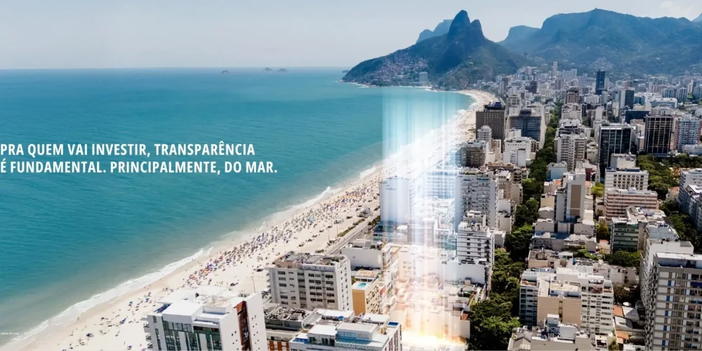 Vista aérea da Praia de Ipanema com destaque para o ponto do empreendimento SAL Praia de Ipanema iluminado, mostrando mar, prédios e o Morro Dois Irmãos ao fundo.