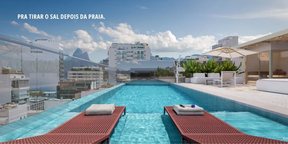 Piscina no rooftop do Sal Praia de Ipanema com espreguiçadeiras vermelhas e vista ampla para o Dois Irmãos e o céu aberto.
