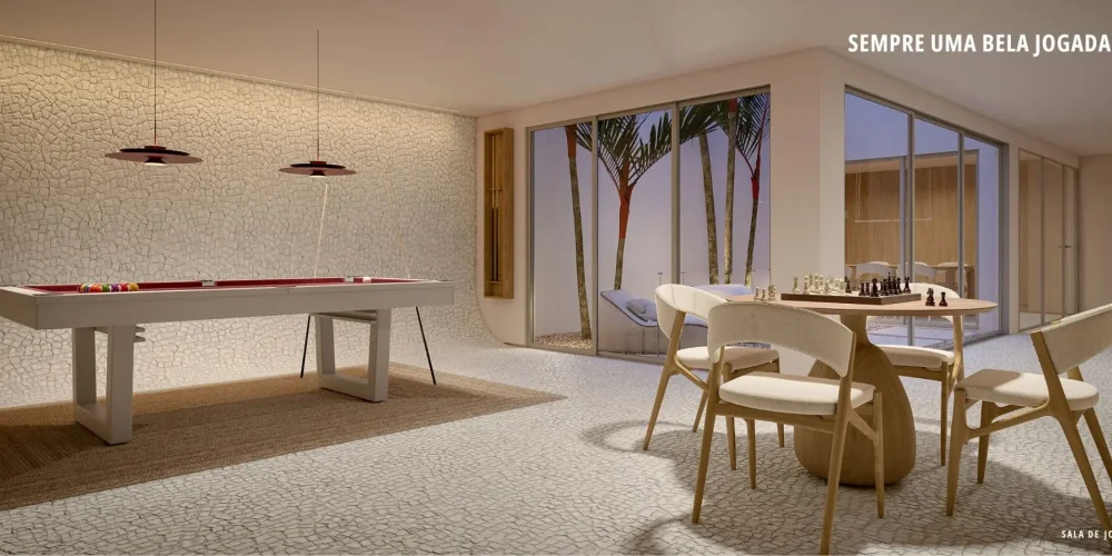 Sala de jogos do Sal Praia de Ipanema com mesa de sinuca branca, mesa de xadrez, cadeiras de madeira clara e vista para o jardim interno.